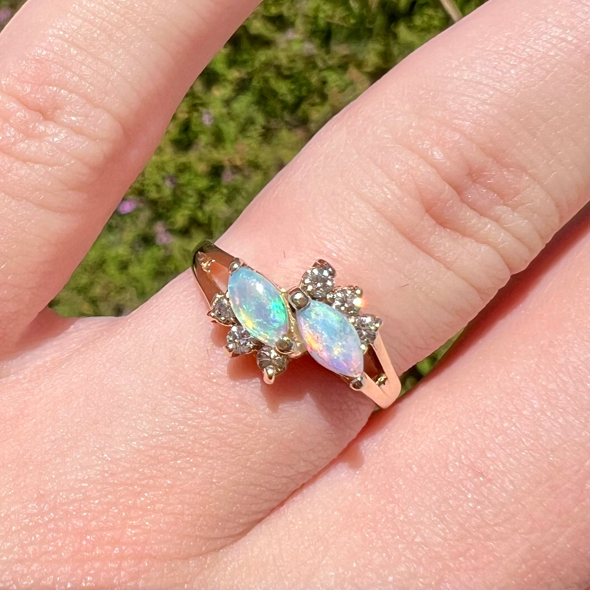 A yellow gold ring mounted with two marquise cut opals and accented with six round diamonds.