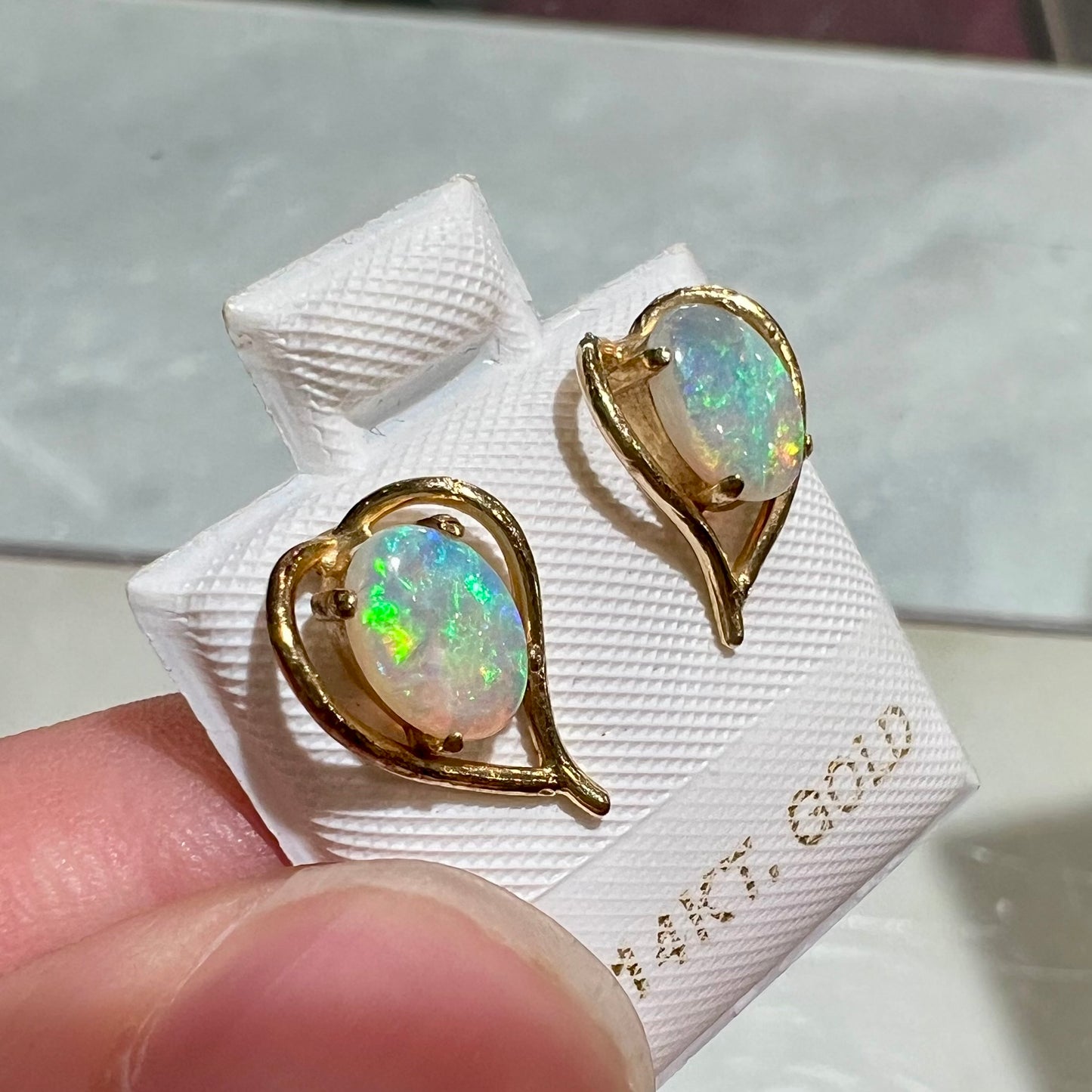 A pair of yellow gold, heart shaped stud earrings set with oval cabochon cut natural opal stones.