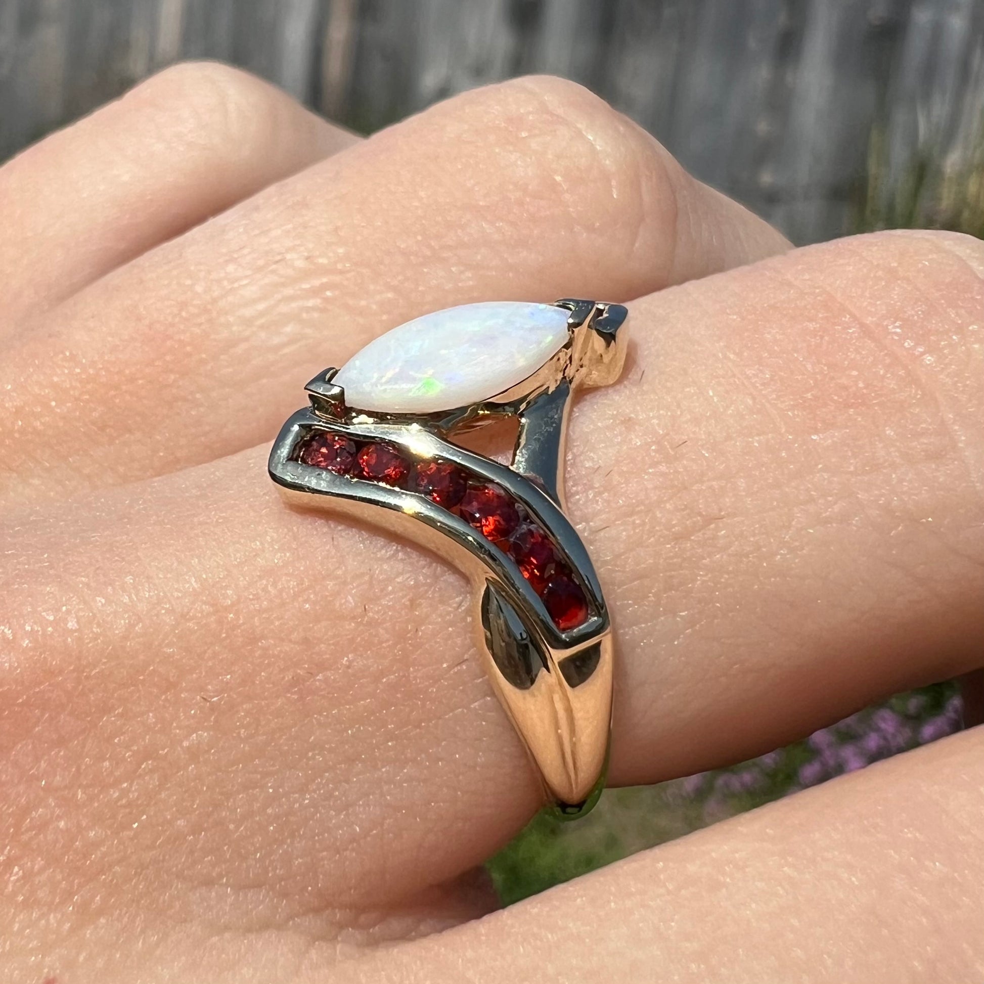 A marquise cut white opal ring.  The ring is accented with channel set reddish orange garnets.