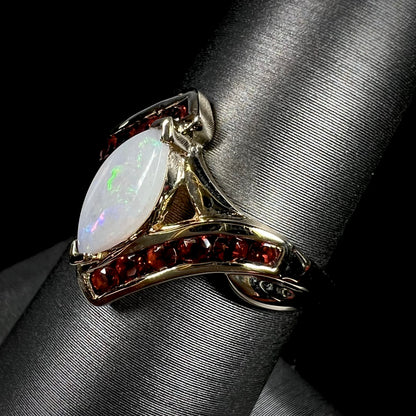 A marquise cut white opal ring.  The ring is accented with channel set reddish orange garnets.