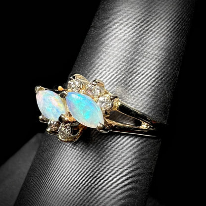 A yellow gold ring mounted with two marquise cut opals and accented with six round diamonds.