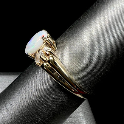 A yellow gold ring set with a natural Australian opal and tapered baguette cut cubic zirconia accents.