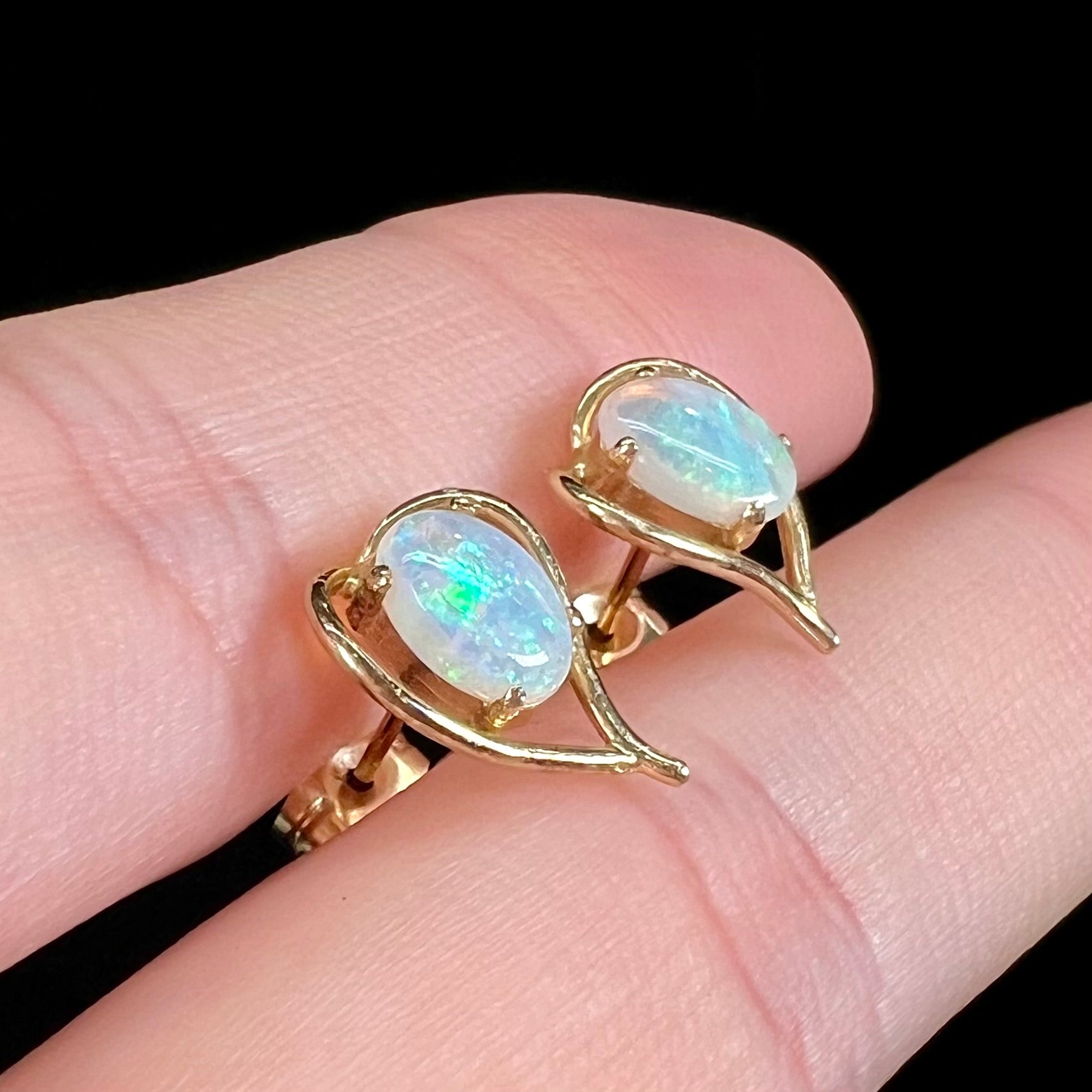 A pair of yellow gold, heart shaped stud earrings set with oval cabochon cut natural opal stones.