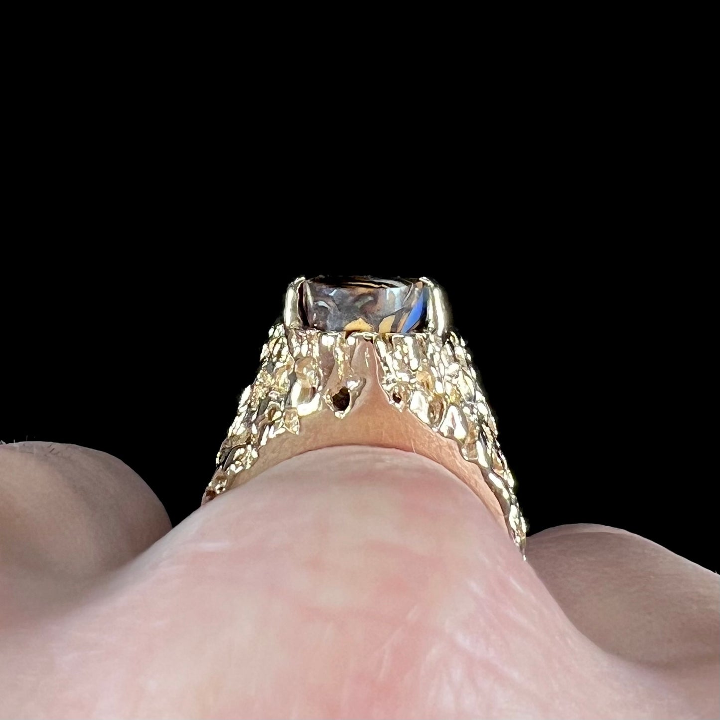 A yellow gold solitaire ring mounted with a Koroit boulder opal stone that shows the picture of a peacock.