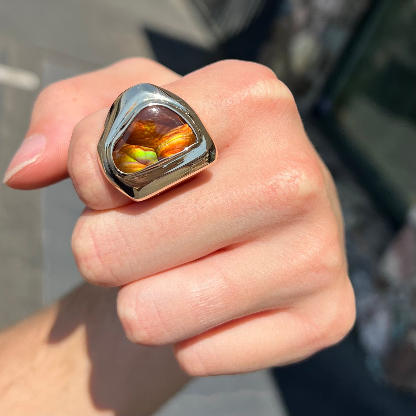 A heavy, yellow gold men's ring mounted with a Mexican fire agate stone.  The fire agate has orange, green, red, and purple colors.