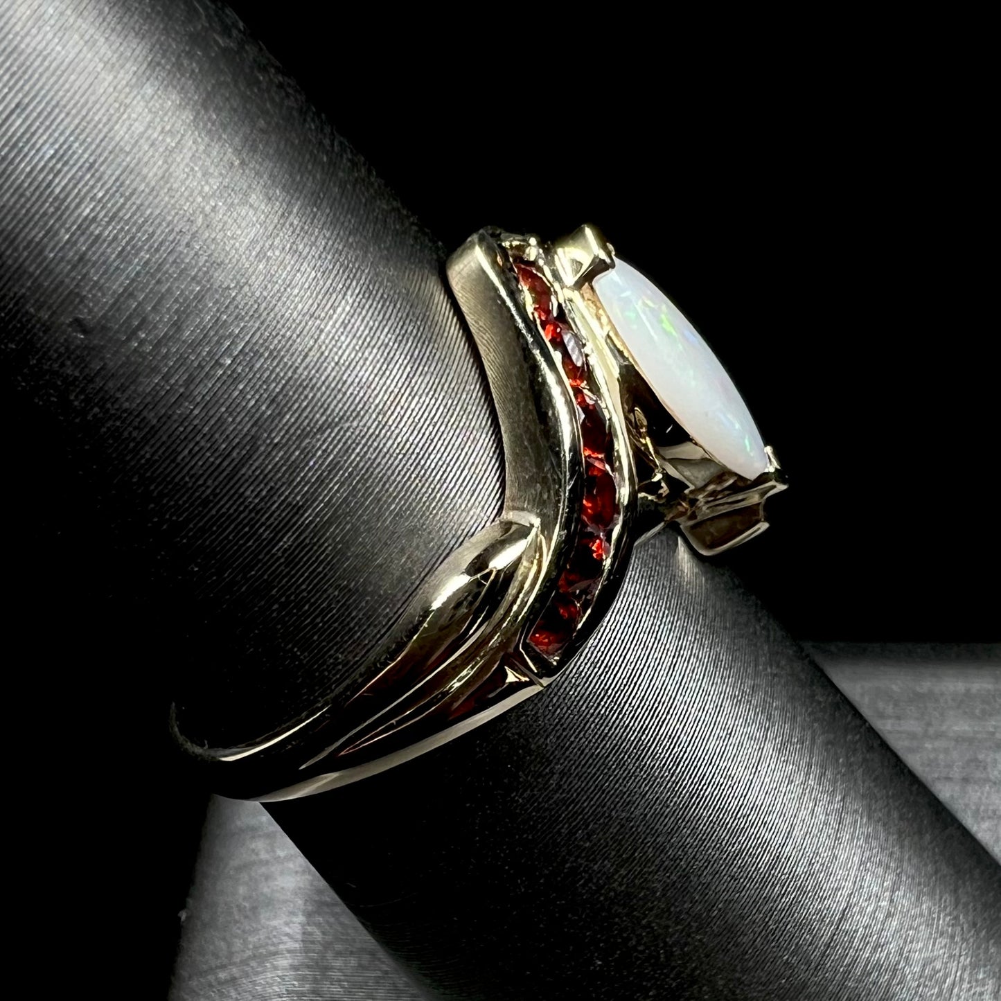 A marquise cut white opal ring.  The ring is accented with channel set reddish orange garnets.