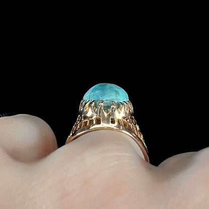 A yellow gold filigree style ring mounted with an oval Pilot Mountain turquoise stone.