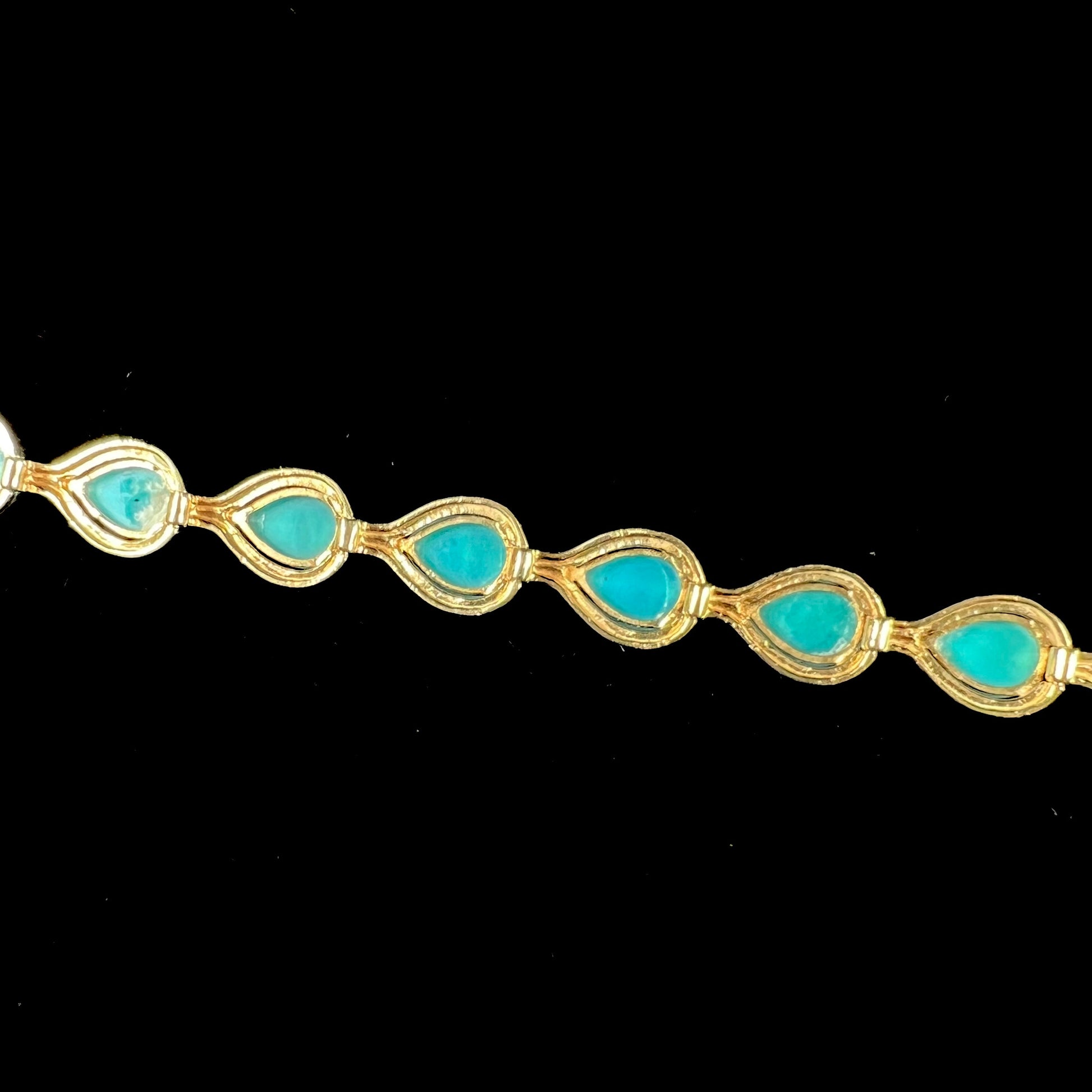 A ladies' yellow gold tennis style bracelet set with pear cabochon shaped natural Sleeping Beauty turquoise stones.