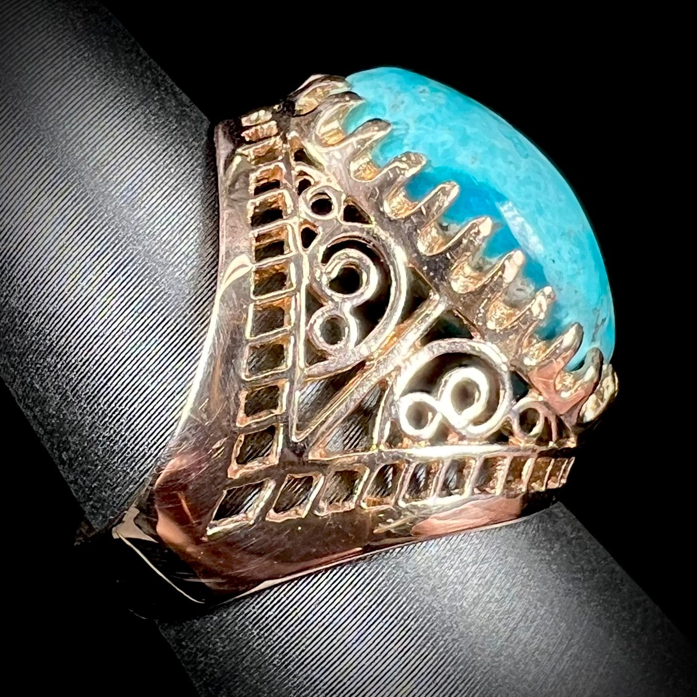 A yellow gold filigree style ring mounted with an oval Pilot Mountain turquoise stone.