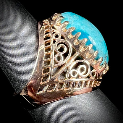 A yellow gold filigree style ring mounted with an oval Pilot Mountain turquoise stone.