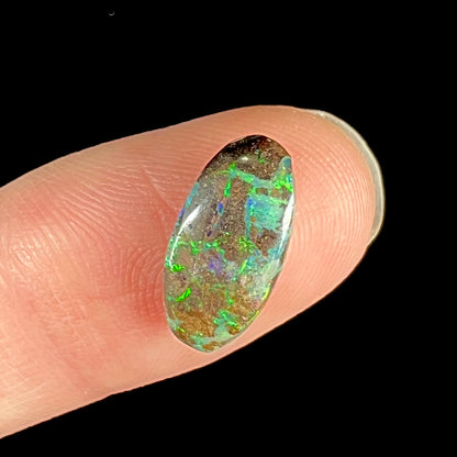 A loose, oval cabochon cut Koroit boulder opal stone.  The opal has a bright green color.