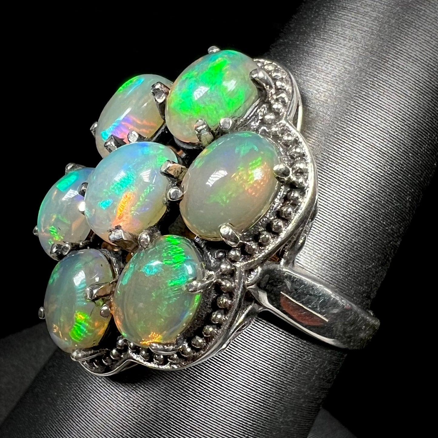 A sterling silver cluster ring prong-set with seven green Ethiopian fire opals.