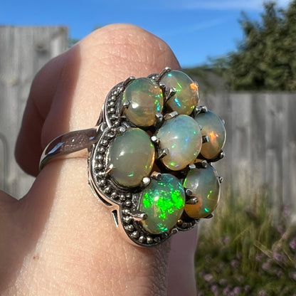 A sterling silver cluster ring prong-set with seven green Ethiopian fire opals.