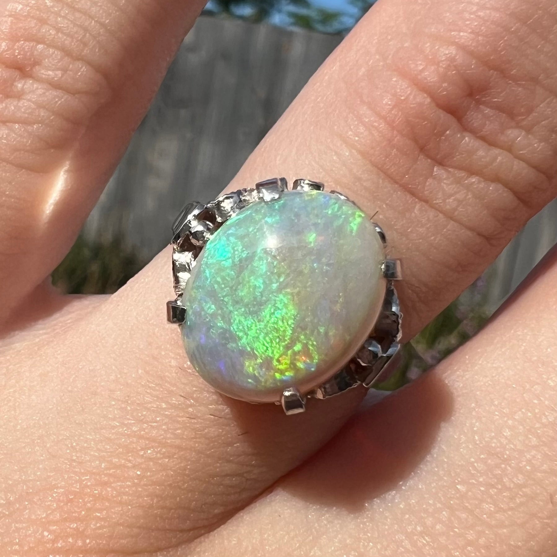 A ladies' Australian opal solitaire engagement ring mounted in platinum.  The opal has green and blue colors.