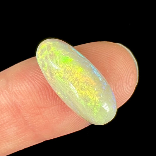 An oval cabochon cut opal from Andamooka, Australia.  The opal has green and orange color play.