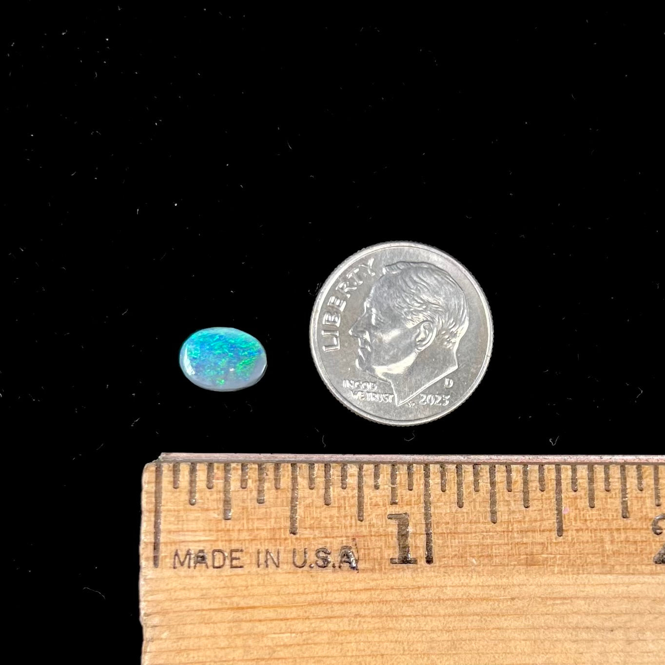 An oval cabochon cut loose Black opal stone from Lightning Ridge, Australia.