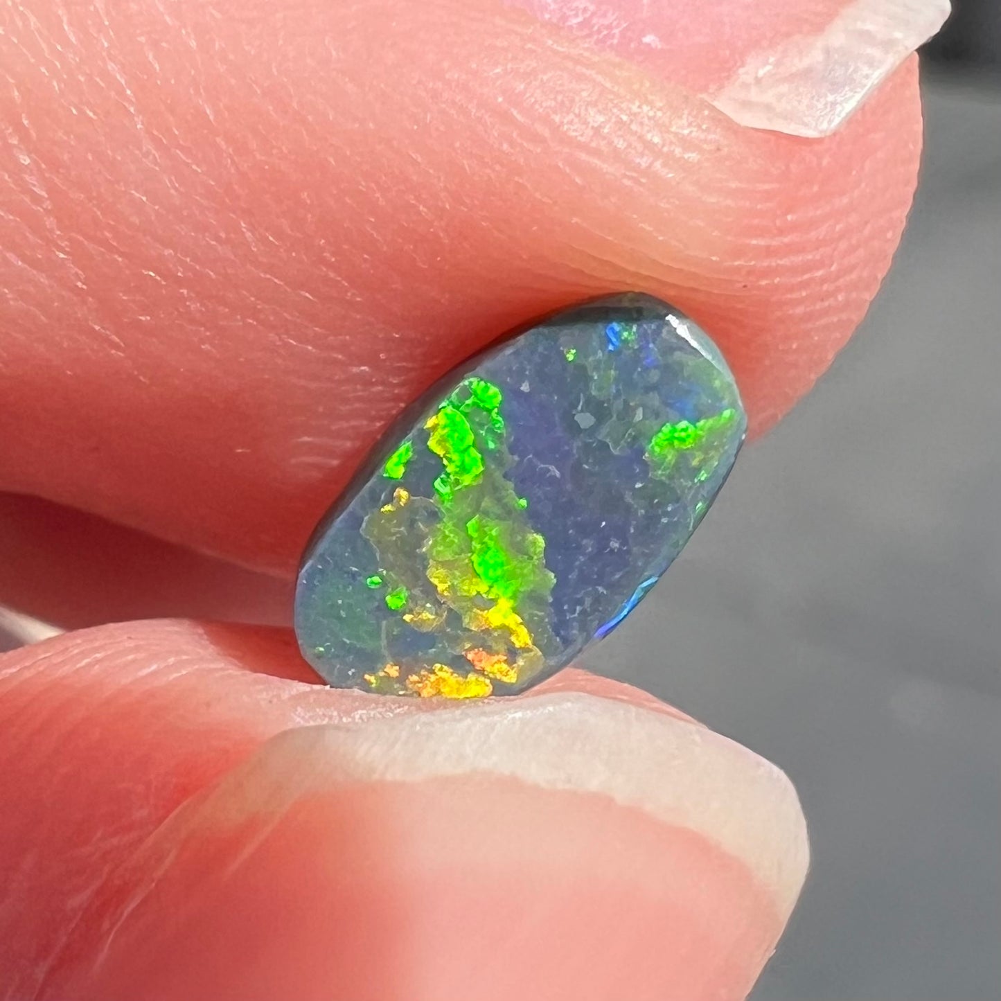 A loose, barrel shaped black opal stone from Lightning Ridge, Australia.