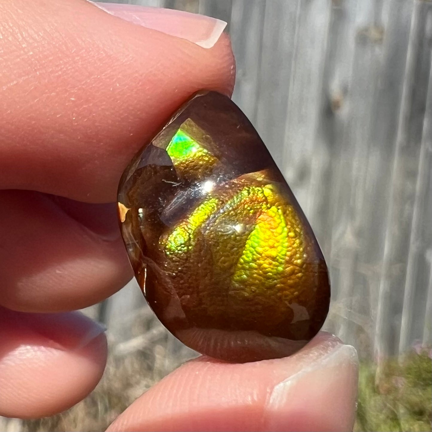 A brightly reflective Mexican fire agate cabochon.  The stone has a strong green iridescence.