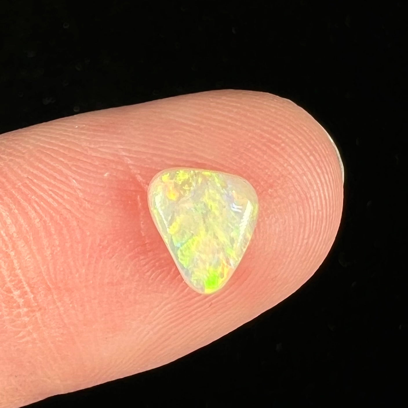 A loose triangular cabochon cut opal from Coober Pedy, Australia.