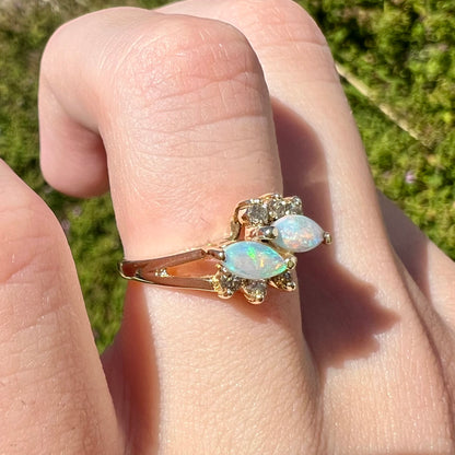 A yellow gold ring mounted with two marquise cut opals and accented with six round diamonds.