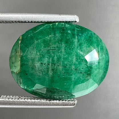 A loose, faceted oval cut commercial grade emerald stone.