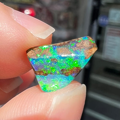 A loose boulder opal stone with bright green and blue fire.