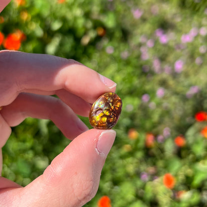 A loose, oval cabochon cut fire agate gemstone.  The stone is bubbly green with blue overtones.