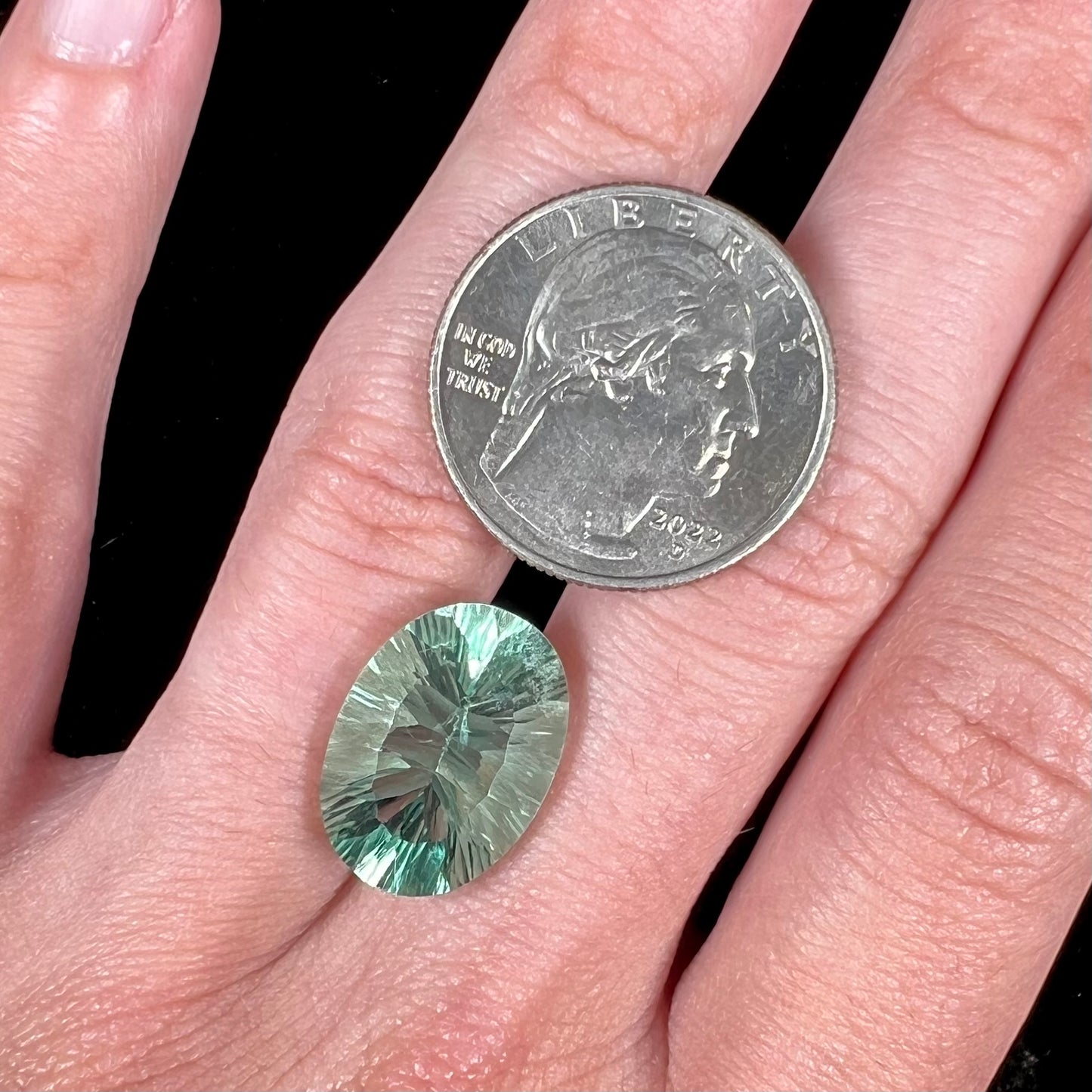 A loose, faceted oval cut mint green fluorite gemstone.