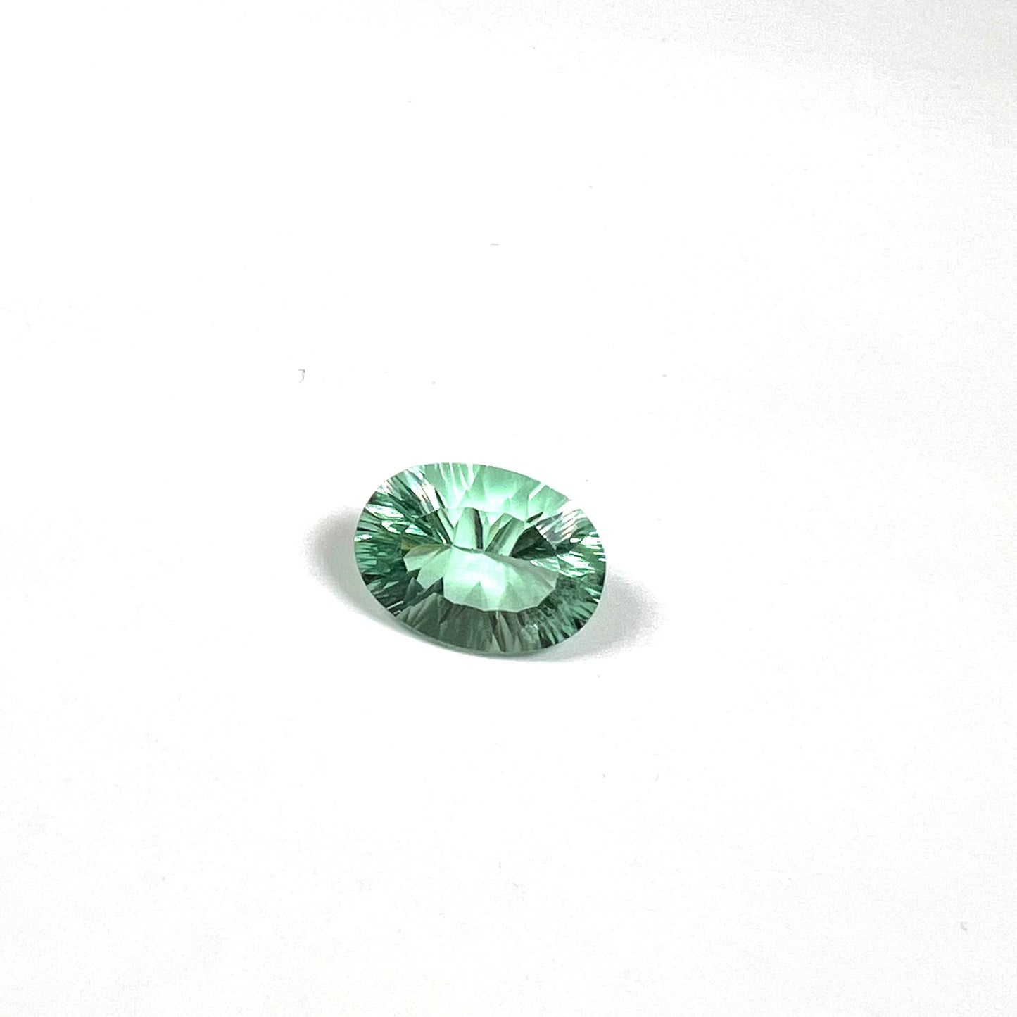 A loose, faceted oval cut mint green fluorite gemstone.