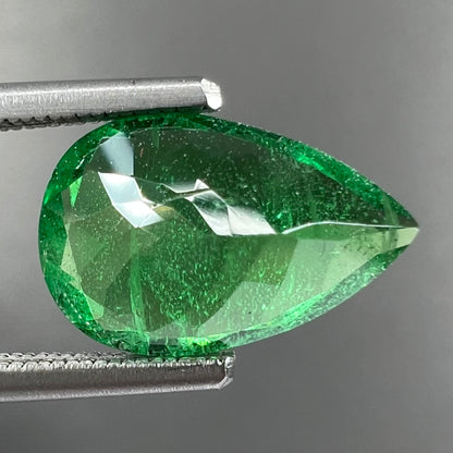 A loose, pear shaped tsavorite garnet gemstone.  The stone is vivid green color.