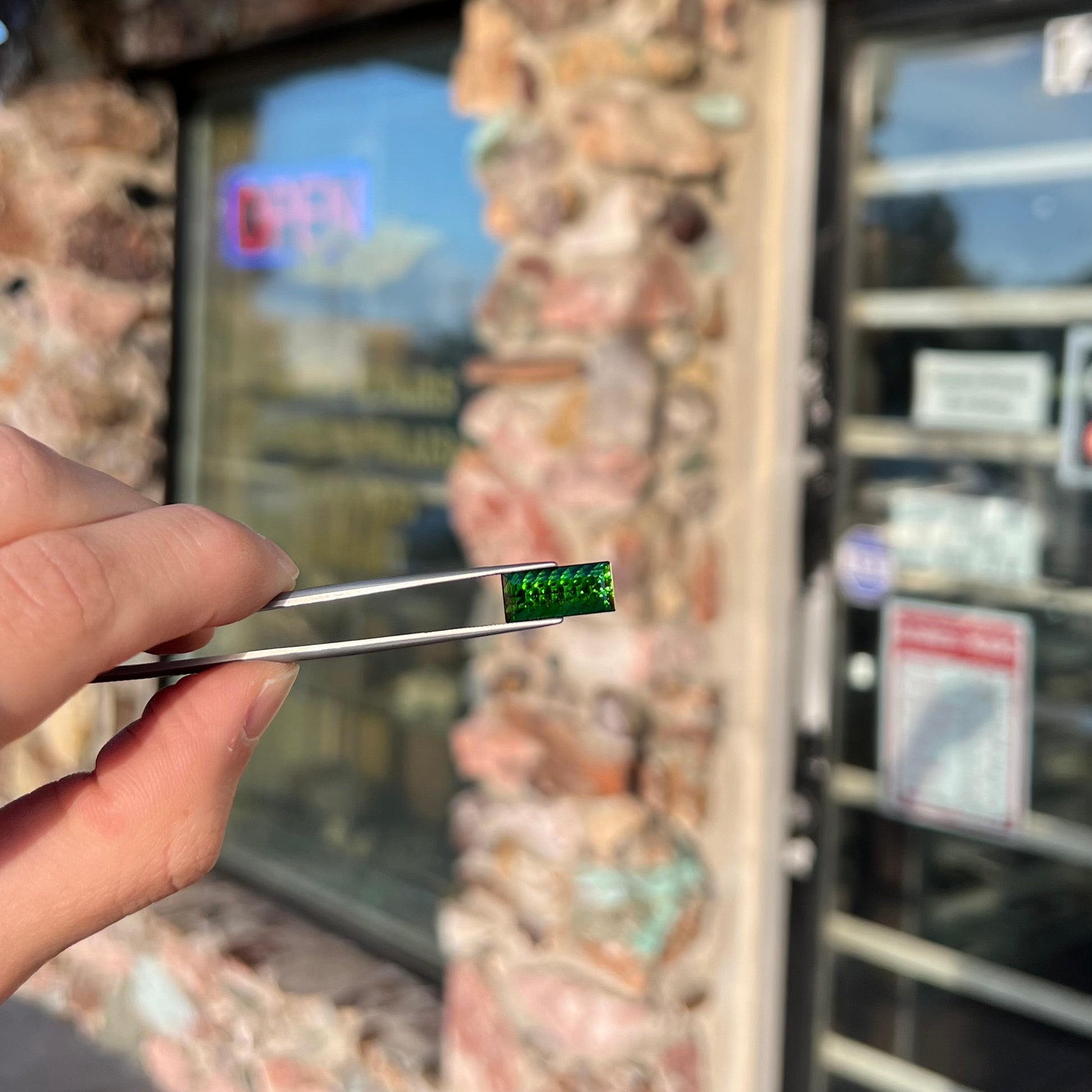 A loose, rectangular laser cut green tourmaline gemstone.