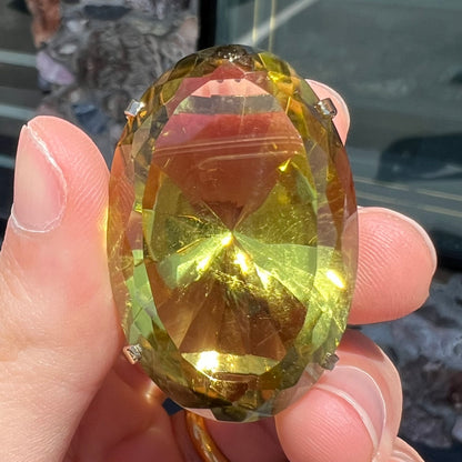 A faceted oval cut lemon quartz gemstone pendant in gold plated sterling silver.  The quartz is a green-yellow color.