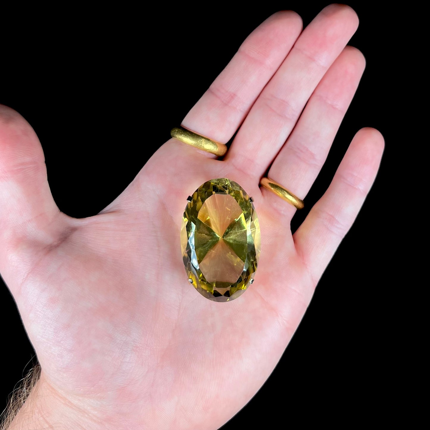 A faceted oval cut lemon quartz gemstone pendant in gold plated sterling silver.  The quartz is a green-yellow color.