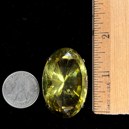 A faceted oval cut lemon quartz gemstone pendant in gold plated sterling silver.  The quartz is a green-yellow color.