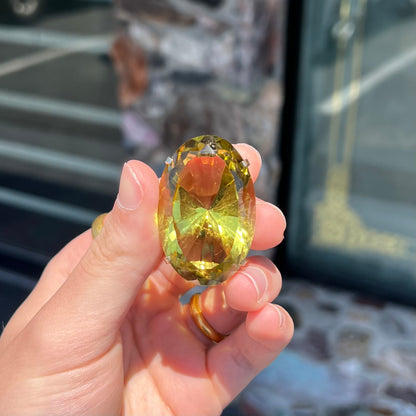 A faceted oval cut lemon quartz gemstone pendant in gold plated sterling silver.  The quartz is a green-yellow color.