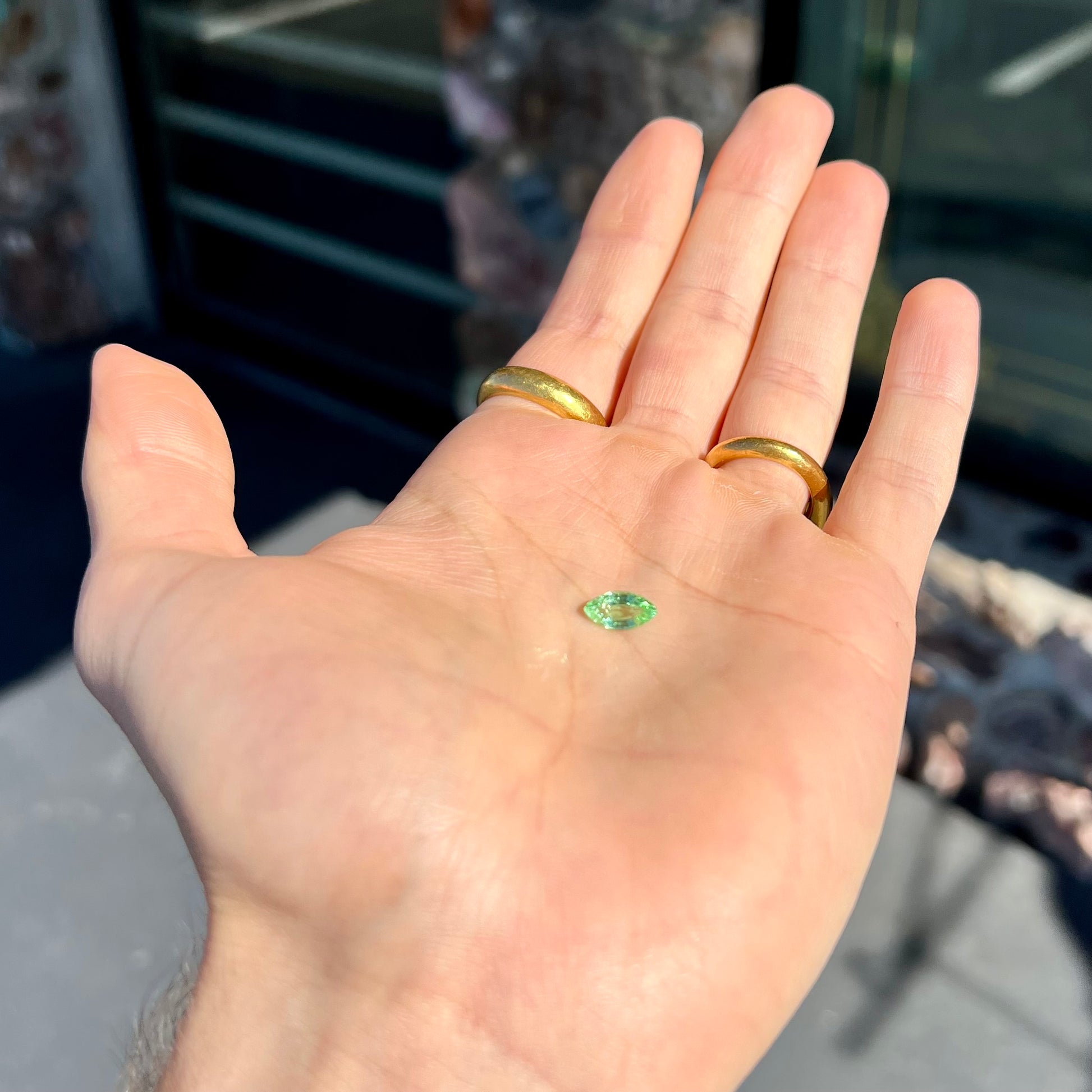 A faceted marquise cut electric green tourmaline gemstone.  The stone has an eye-visible rutile needle inclusion.