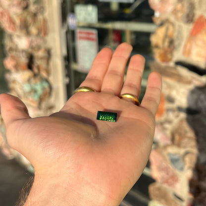 A loose, rectangular laser cut green tourmaline gemstone.