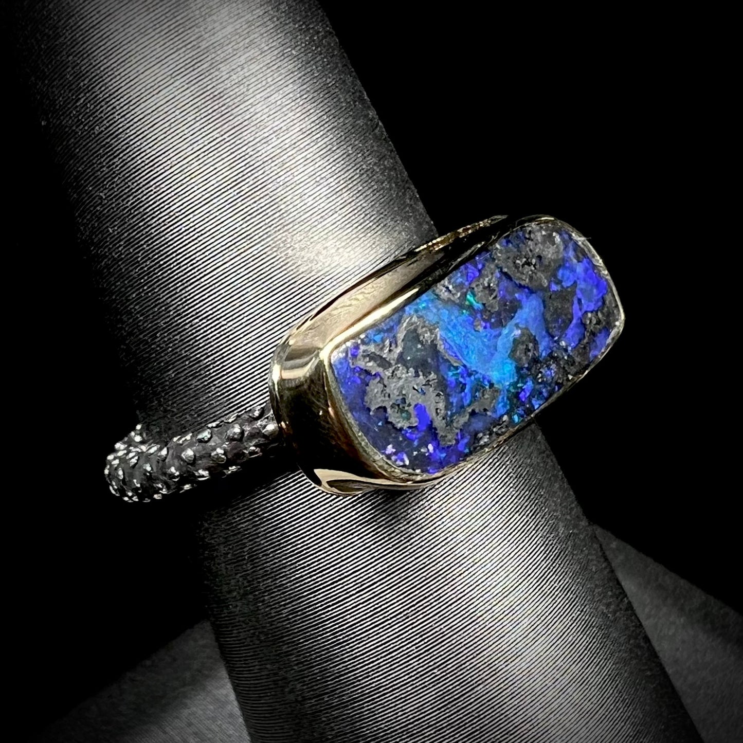 A two-tone sterling silver and 18k gold ring set with a blue boulder opal stone.  The shank is textured.