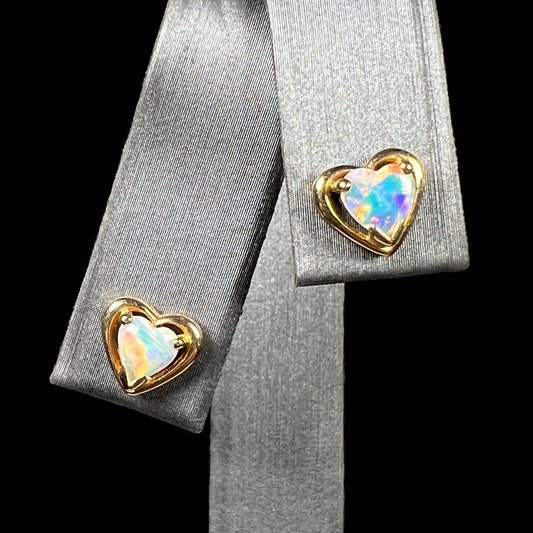 A pair of yellow gold stud earrings mounted with heart shaped natural crystal opals.