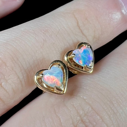 A pair of yellow gold stud earrings mounted with heart shaped natural crystal opals.