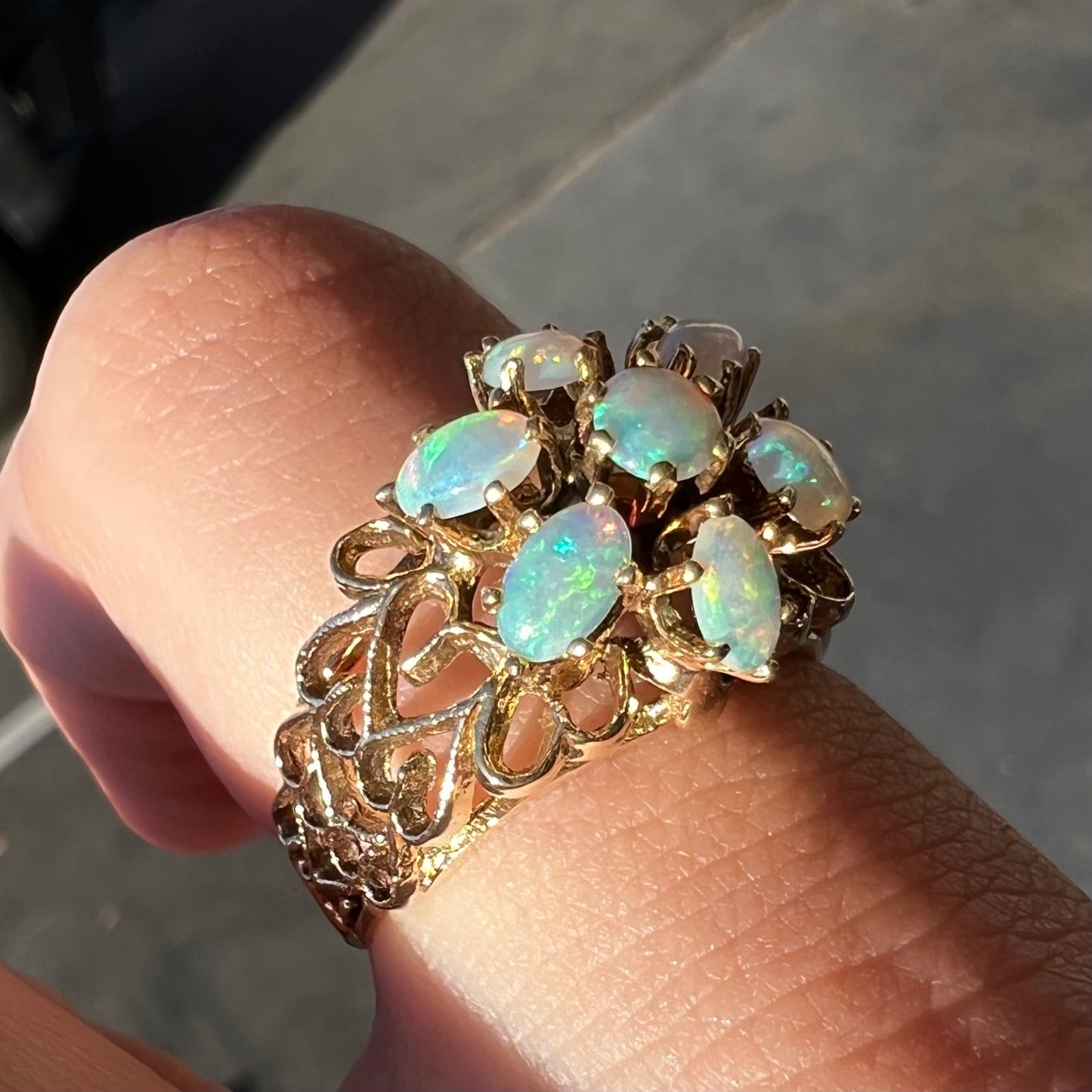 A vintage, 1950's style opal cluster ring cast in yellow gold with a heart shaped filigree design.