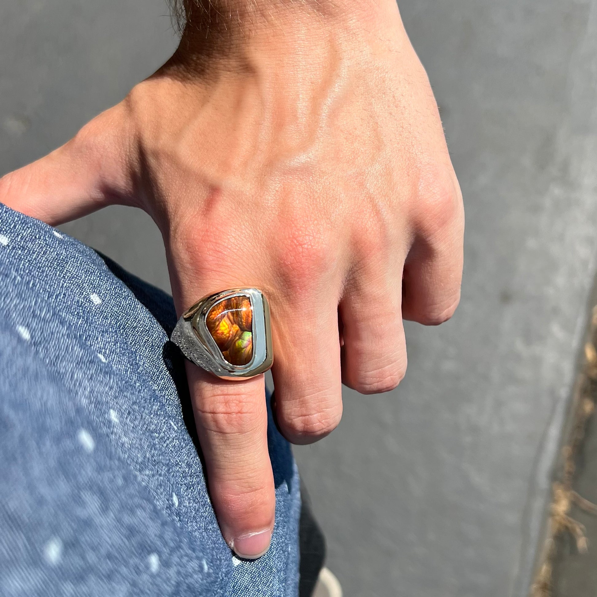 A heavy, yellow gold men's ring mounted with a Mexican fire agate stone.  The fire agate has orange, green, red, and purple colors.