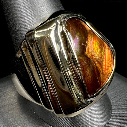 A heavy, yellow gold men's ring mounted with a Mexican fire agate stone.  The fire agate has orange, green, red, and purple colors.