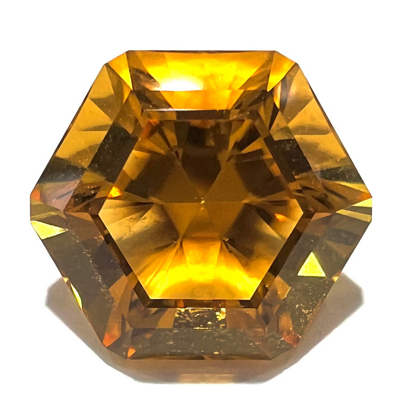 A loose, faceted hexagon cut citrine gem.  The stone is golden yellow color.