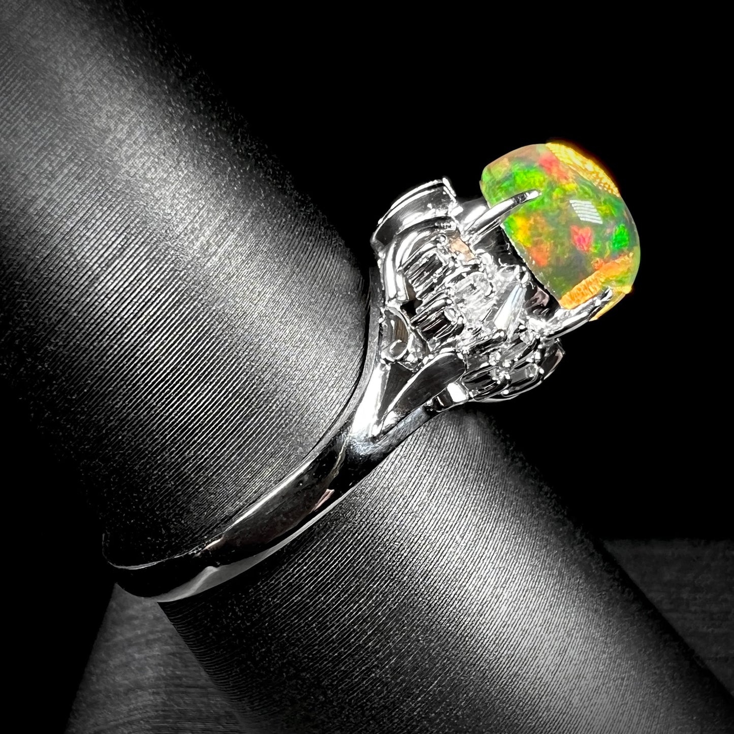 A platinum filigree ring mounted with a high-domed Mexican fire opal and baguette cut diamond accents.