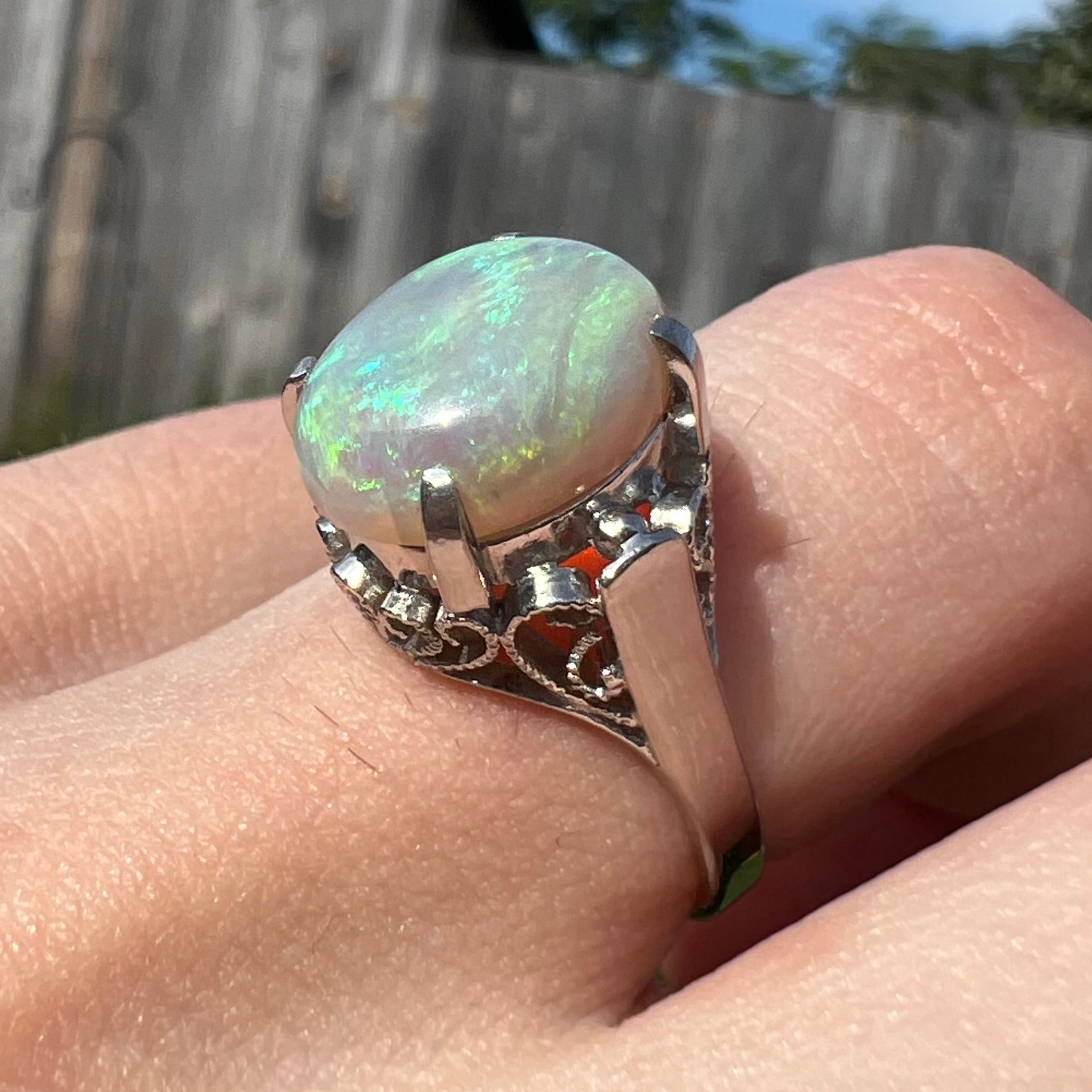 A ladies' Australian opal solitaire engagement ring mounted in platinum.  The opal has green and blue colors.