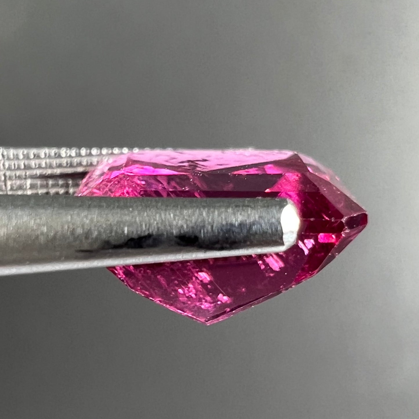 A loose, faceted modified emerald cut hot pink tourmaline stone.