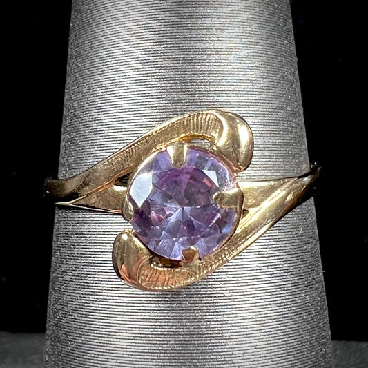 A vintage 1960's yellow gold ring set with a round synthetic purple alexandrite.  The prongs are worn.