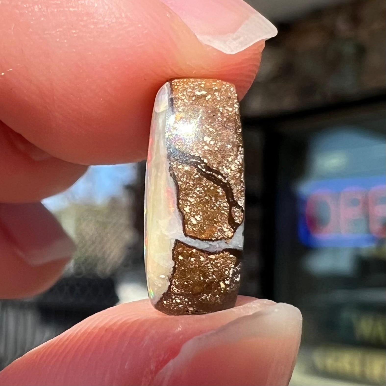 An oval cabochon cut boulder opal from Quilpie, Australia.  The opal has multicolor color play.