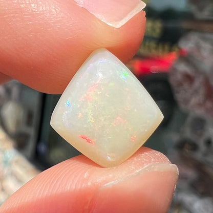 A loose, kite shaped white opal stone from Coober Pedy, Australia.  The stone has subdued red colors.